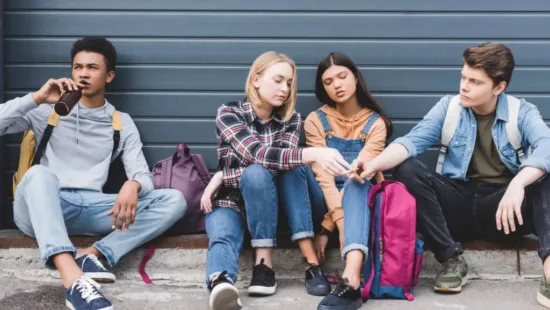 Vier jongeren die op de grond zitten en een sigaret doorgeven